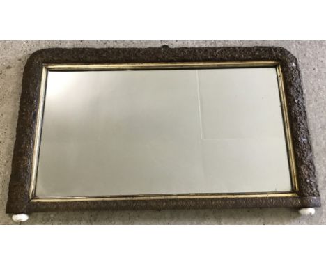 A vintage mantel mirror with ornate carved decoration to frame and bun feet.  Approx. 50cm x 80cm.