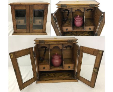 An oak 2 door smokers cabinet with bevel edged glass panels and hinged top. Internal compartments, pipe racks and 2 drawers. 