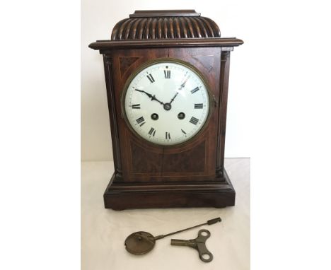A Victorian wooden cased mantle clock with enamel face  and classic detail. Complete with pendulum and key. 