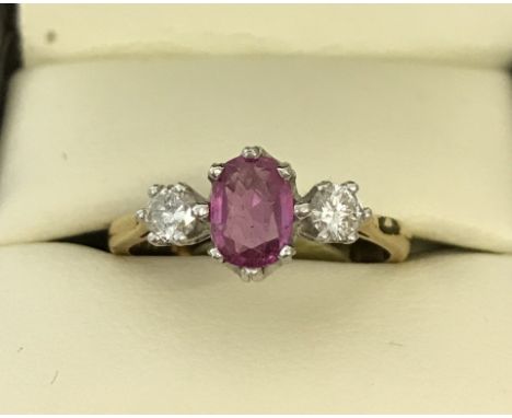 An 18ct yellow gold, 3 stone ruby and diamond dress ring. Central oval cut ruby, approx. 1.3ct, flanked by 2 round cut diamon