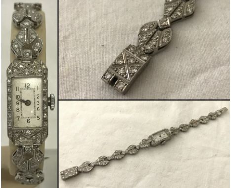 A Ladies Art Deco style platinum and diamond cocktail wristwatch. Diamonds surrounding face of watch, throughout strap and ca