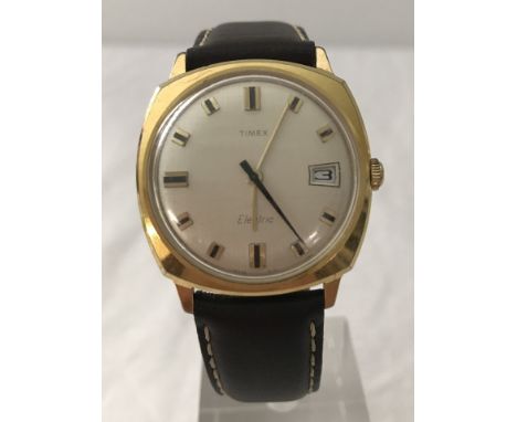 An early mechanical electric Timex watch in brown leather strap. Gold tone case, date calendar, raised batons to face. 
