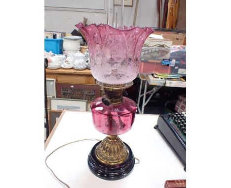 A VICTORIAN OIL LAMP WITH ORIGINAL ETCHED CRANBERRY SHADE note Reservoir and base drilled for electricity