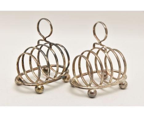 TWO EARLY 20TH CENTURY SILVER TOAST RACKS, both of an oval form with four sections, circular handles and raised on four ball 