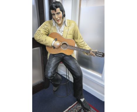 A LIFESIZE FIGURE OF THE WORLD FAMOUS ROCK AND ROLL STAR ELVIS PRESLEY, seated on a stool, playing a guitar, height approxima