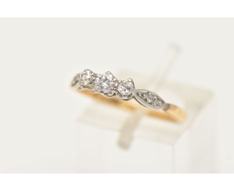 A YELLOW METAL DIAMOND THREE STONE RING, designed as a central round brilliant cut diamond, flanked with two old cut diamonds
