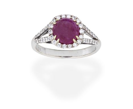 RUBY AND DIAMOND CLUSTER RINGThe cabochon ruby within a brilliant-cut diamond surround, between bifurcated shoulders, set wit