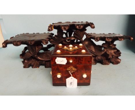 An amboyna tea caddy, applied gilt metal mounts with white cabochons, 12 cm wide, and a Chinese carved hardwood stand (2) Con