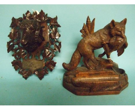 An early 20th century Black Forest style carved wood inkstand, in the form of a fox carrying a dead bird, 16 cm high, and a s