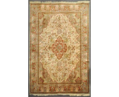 A cream and grey ground large carpet, the centre with red ground quatrefoil medallion, woven with equestrian archers in woods