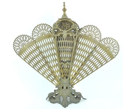 A cast brass peacock fire screen having a nine section fan each with pierced peacock feather decoration, all raised on an aca