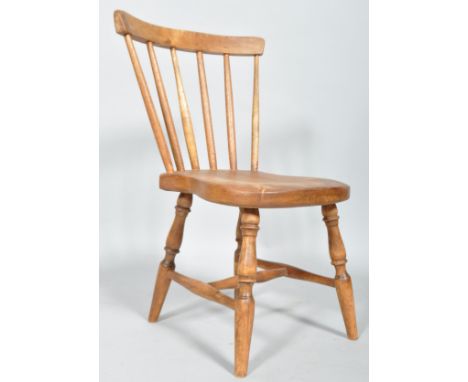 An elm child's stick back kitchen chair, with curved top rail and spindle back, on turned baluster legs and cross stretchers,