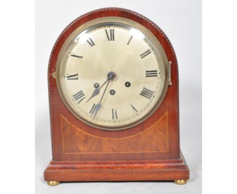 An Edwardian mahogany and inlay arch top mantle clock with carved edge, roman numeral dial, chiming movement, the case raised