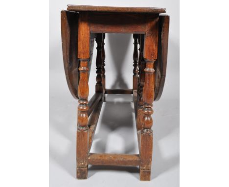 A late 18th century oak circular drop leaf gate leg dining table with one short drawer above turned baluster legs and plain s