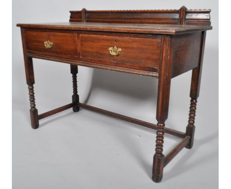 An Edwardian Harris Lebus oak side table, fitted with two drawers, on turned supports, 88cm high x 114cm wide