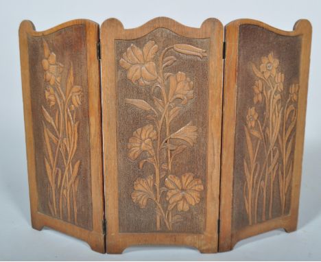 An Art  Nouveau oak three section fire screen, with carved floral decoration, 57cm high