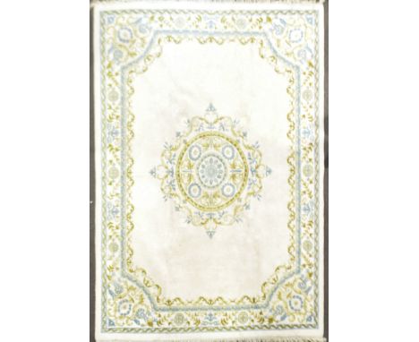 A large wool Indian carpet, of neo-classical design with an ochre and yellow and blue scroll border with hexagonal medallions