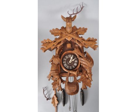 A German  carved wooden Cuckoo clock, surmounted with a stag, game and with a small door issuing a cuckoo, with German mechan