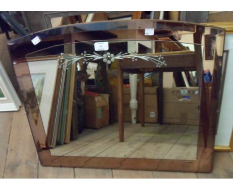 A vintage frameless wall mirror with bevelled peach coloured border and engraved stylised floral spray to main plate