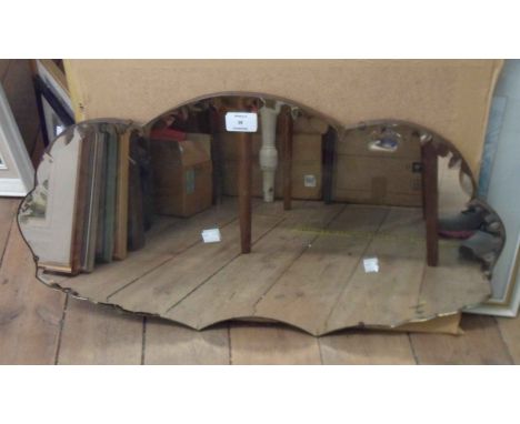 A vintage frameless wall mirror with decorative cut border to shaped plate