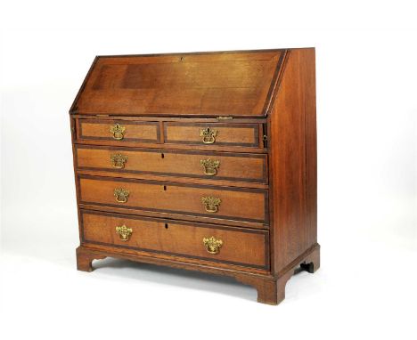 A George III country oak cross-banded bureau with a caddy top above a tambour front enclosing a fitted interior above two sho