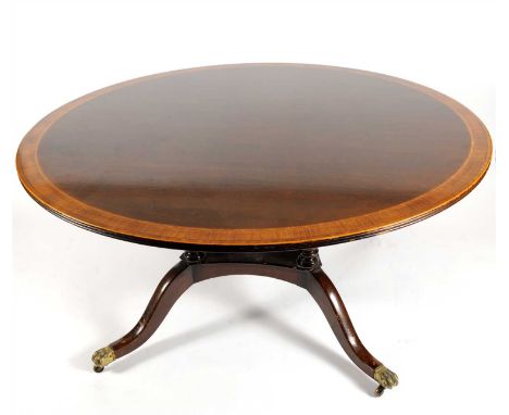 A reproduction cross-banded mahogany dining table, the circular bordered top raised on four turned columns above four swept l