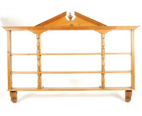 A three-sectional pine kitchen wall rack with architectural pediment centred by an urn finial above three open shelves spaced