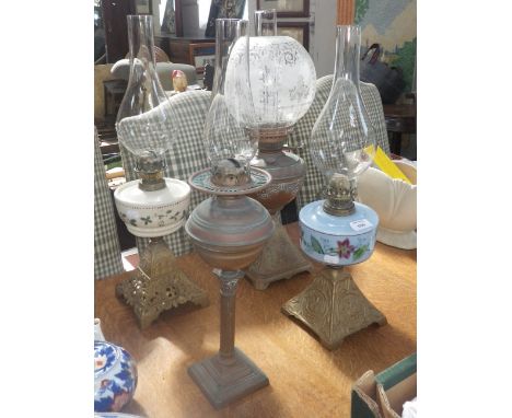 A Victorian oil lamp with blue glass reservoir and cast iron foot, three others similar, one with original etched shade  