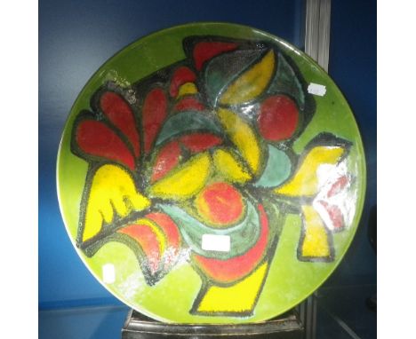 A large Poole Pottery 'Delphis' type charger, decorated in red, blue, green and yellow 