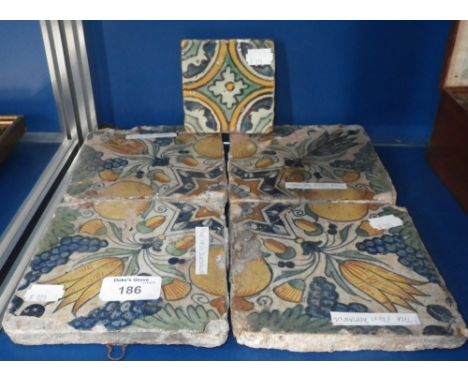 A set of four polychrome tiles decorated with flowers and fruit and another similar smaller tile 
