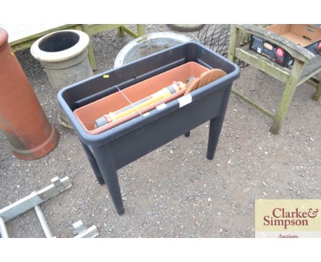 A plastic planter and contents of a plant stand on wheels, a garden sprinkler etc