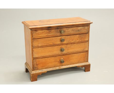 A MID-19TH CENTURY PINE MINIATURE CHEST OF DRAWERS, with four graduated drawers with brass pulls, raised on bracket feet. 45c