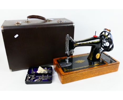 A vintage EB series Singer sewing machine, black with gilt decoration, contained in carry case with accessories. [W]