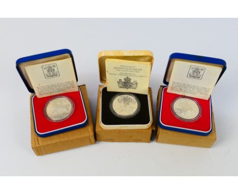 Three silver proof coins comprising two Silver Jubilee examples and a Queen Mother 80th Birthday, all encapsulated and contai