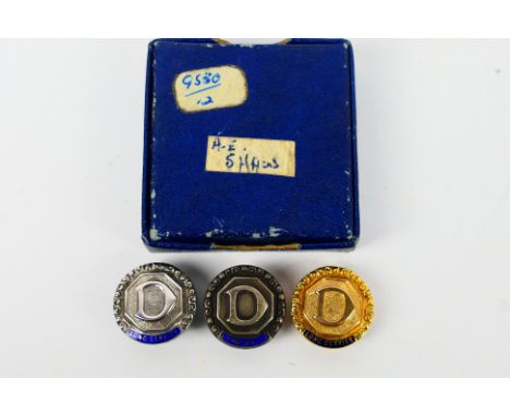 A 9ct yellow gold and enamel Long Service badge for Dunlop, 4.3 grams, and two similar silver examples, contained in a Garrar