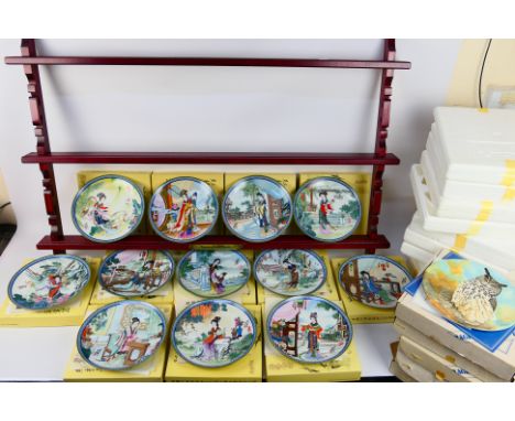A quantity of boxed collector plates to include a set of twelve Beauties Of The Red Mansion with a wall mountable display rac