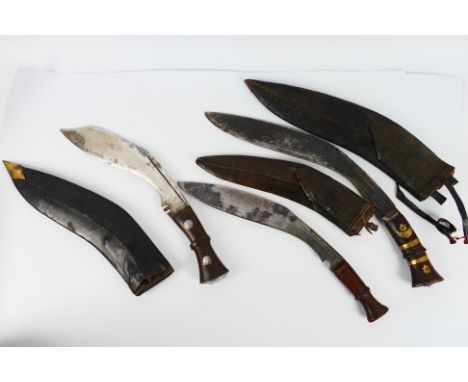Three vintage Kukri, each with scabbards, one marked to the blade with broad arrow, an example with brass mounted hilt and on