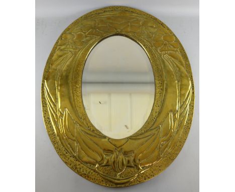 Art Nouveau brass embossed oval mirror   76cm x 61cm  with beveled plate and a similar decorated fender 150cm wide,