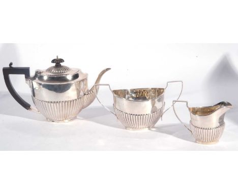 George V silver three piece tea set of oval form with half fluted bodies comprising teapot, sucriere and milk jug, hall marke