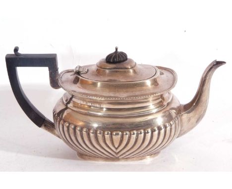 Edward VII silver teapot of oval form having a hinged lid with an ebonised finial, applied gadrooned rim with a curved spout 