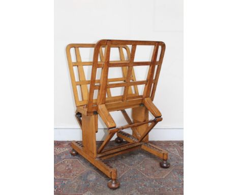 Late 19th century honey-oak folio stand by Gillows of Lancaster, with adjustable lattice supports on H-shaped base and bun fe