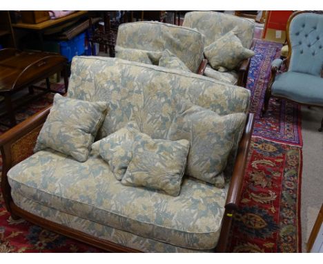 A FINE MID TONED ERCOL THREE PIECE BERGERE SUITE with green and fawn floral upholstery, (all single cane panels in fine order