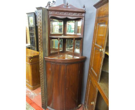 A VICTORIAN MAHOGANY BOW FRONT STANDING CORNER CUPBOARD with mirrored top structure and curved shelf on turned supports, 190 