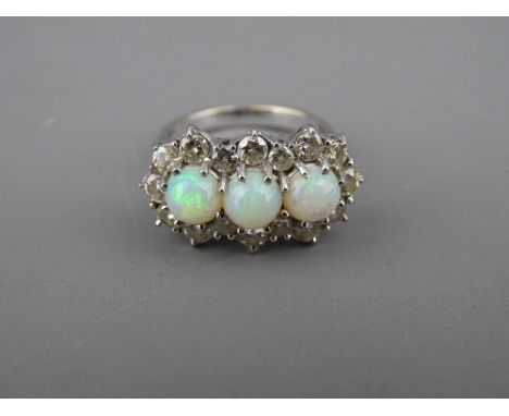 AN EIGHTEEN CARAT WHITE GOLD OPAL &amp; DIAMOND CLUSTER DRESS RING having three round cut opals in an oblong setting with six