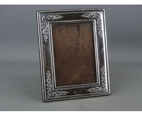 A MODERN SILVER EASEL PORTRAIT FRAME with scrolled decoration to take a picture 12 x 8.5 cms