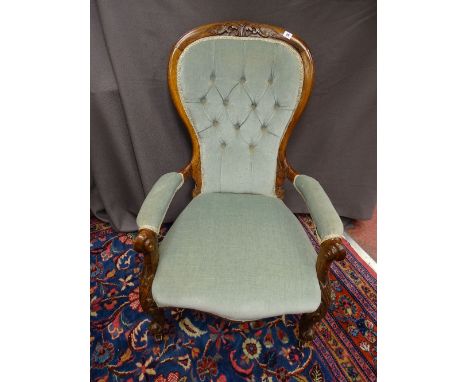 A VICTORIAN WALNUT SPOONBACK ARMCHAIR with carved detail and button back upholstery on brown pot castors, 104 cms high, 67 cm