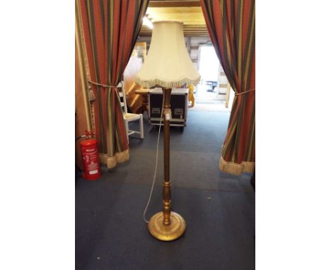 A gilt painted standard lamp with cream shade