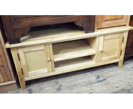 A long low modern light oak entertainment unit fitted shelves and cupboards 