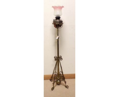 A Victorian adjustable brass standard lamp with oil lamp top and glass shade 