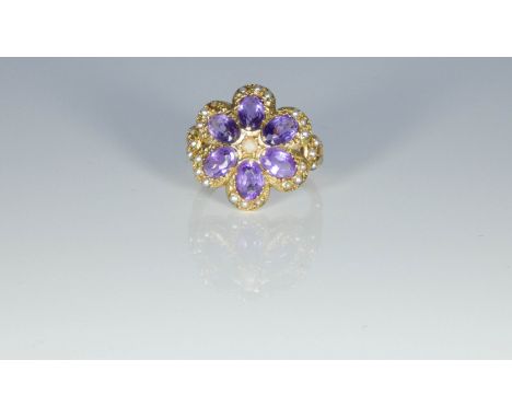 A pretty Edwardian 9ct gold amethyst and seed pearl cluster ring set with six oval amethysts in a flower head design offset w